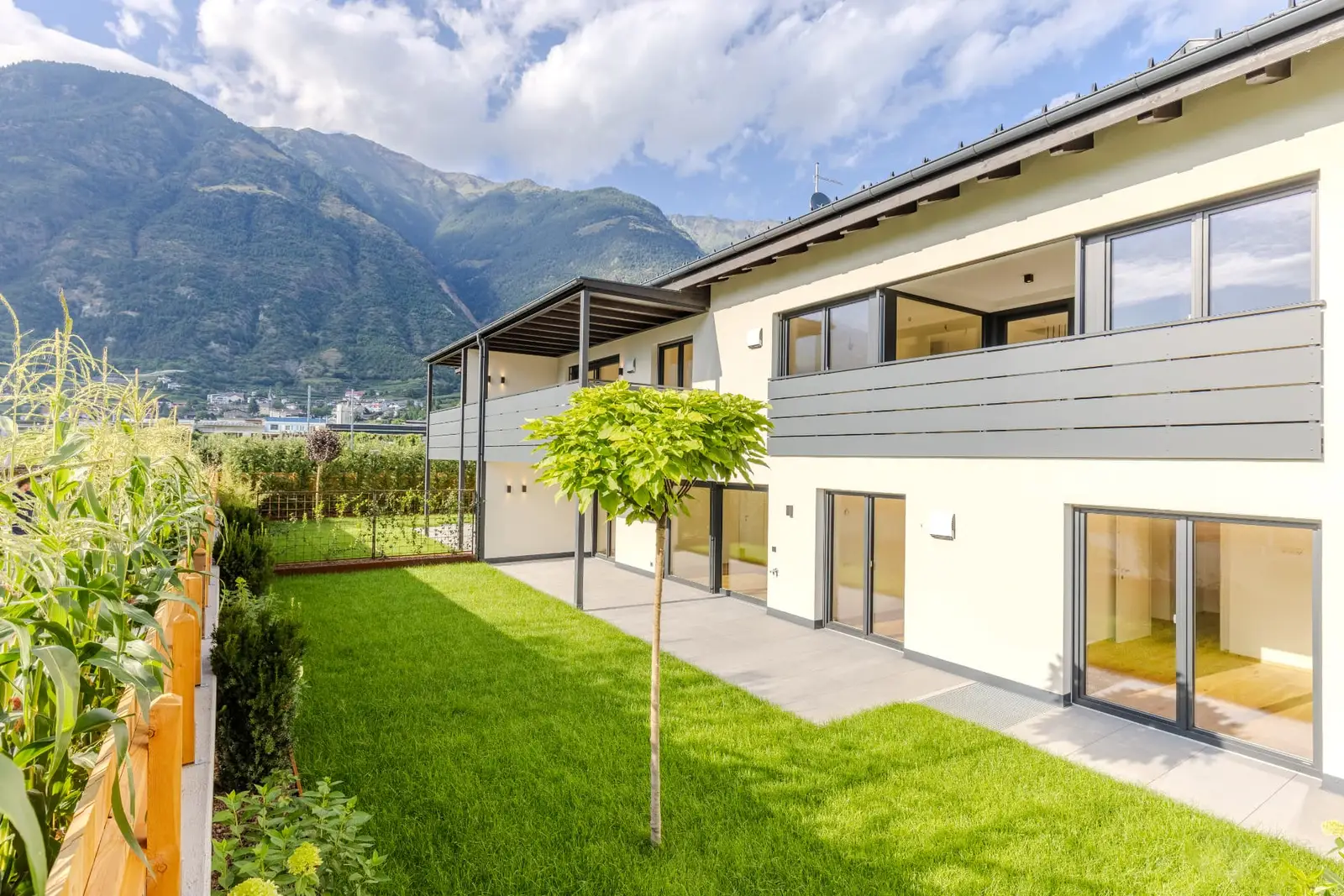 Residence Goldegg Goldrain — Gartenfassade mit überdachten Balkonen vor Bergkulisse